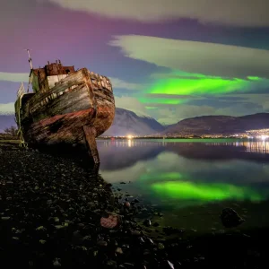 Reflections of the Northern Light captures a rare and magical moment in the Scottish Highlands. This limited edition A4 glossy print shows the aurora borealis dancing above the iconic boat on Caol Beach near Fort William.